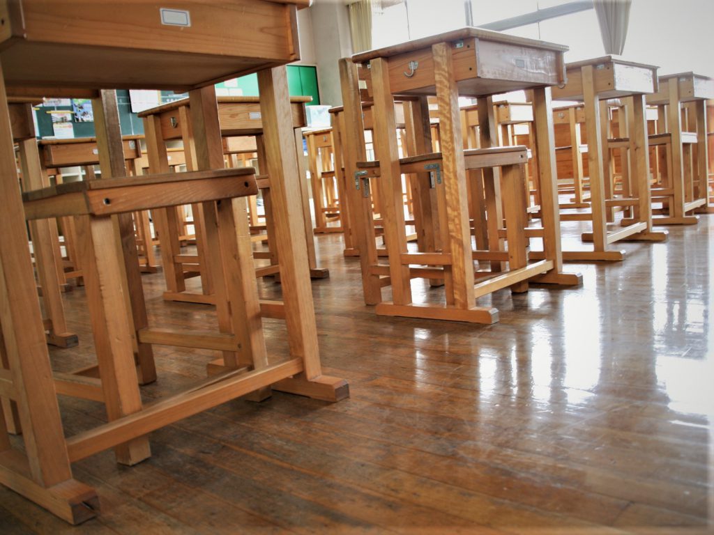 昭和時代を彷彿とさせる木目の椅子と机が並んでいる教室