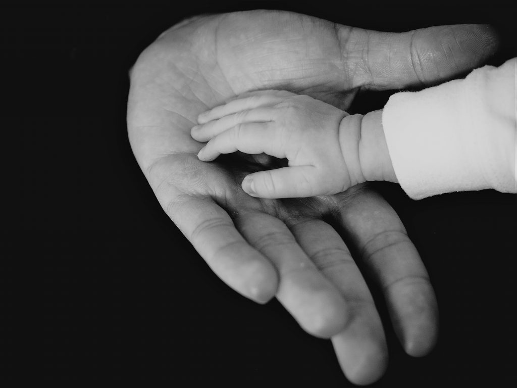 大人の手のひらに赤ちゃんの小さな掌が乗っている白黒写真