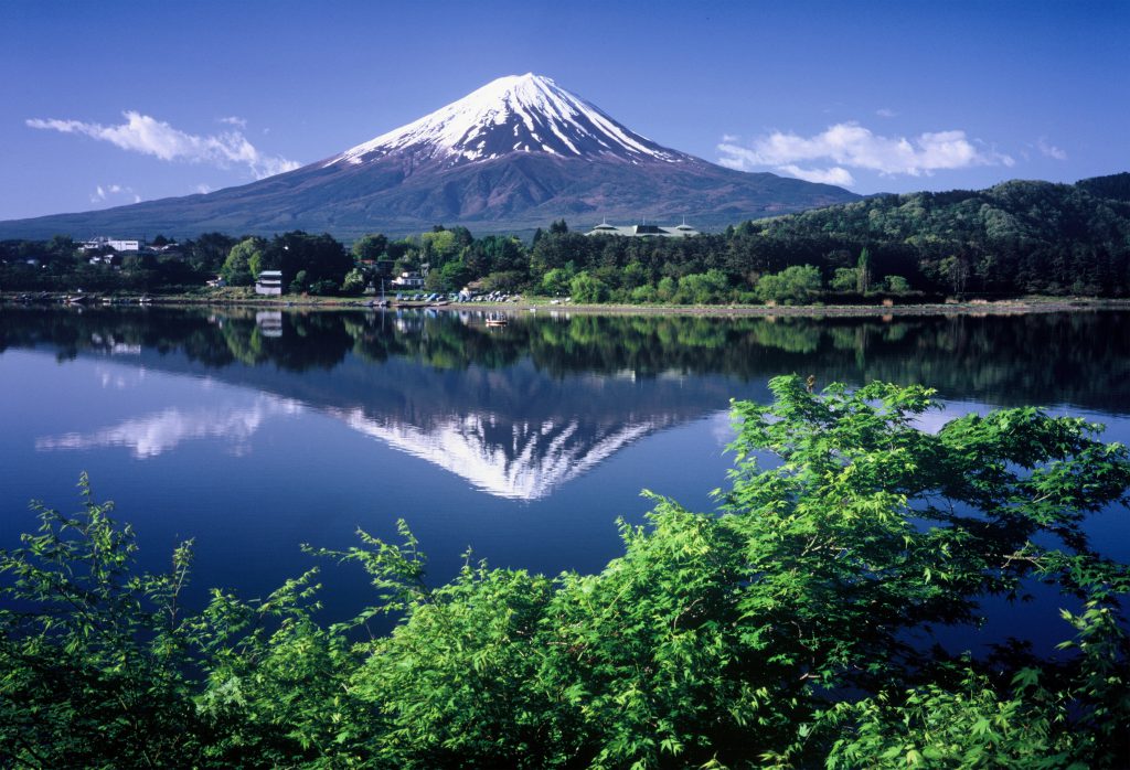 山梨県富士河口湖町の河口湖から見たダイヤモンド富士。夏の済んだ水面に富士山が映っている。