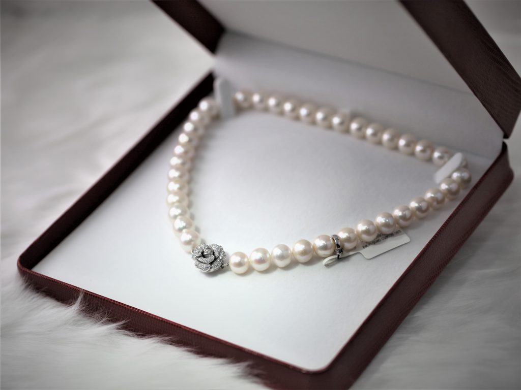 高級なビロードっぽい赤い宝石箱が開いていて中から真珠のネックレスが見える。一連真珠でトップにはダイアモンドの花モチーフ。