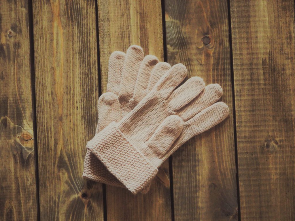 木目調の床にメリヤス編みのピンク色の手袋
