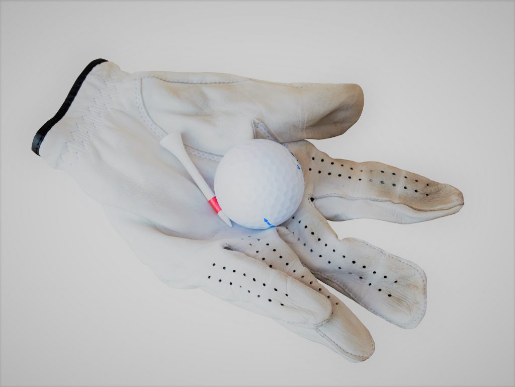使い込んだゴルフ用の白い手袋にゴルフボールが1個乗っている写真