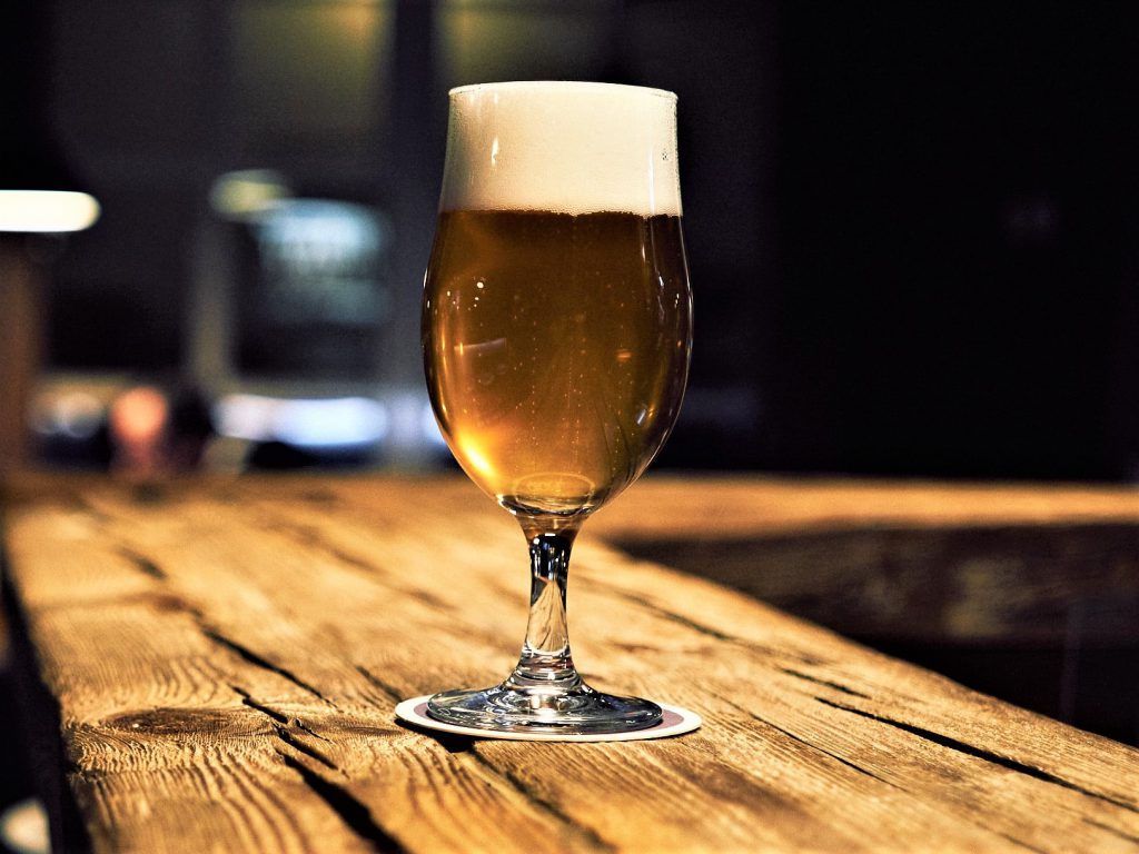 ウッド調のおしゃれなバーカウンターにグラスビールが１杯飾られている様子。
