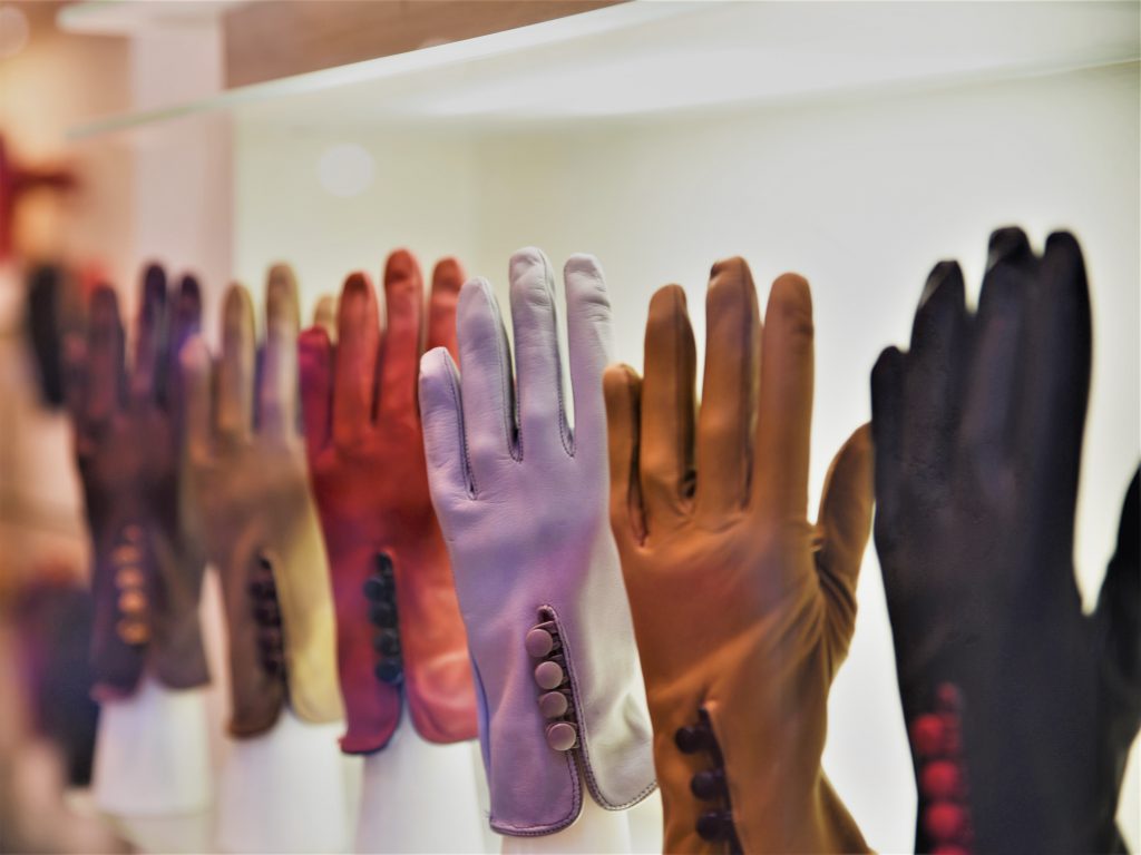 黒・茶色・紫・赤などカラフルな革の手袋がお店の中で展示されている写真