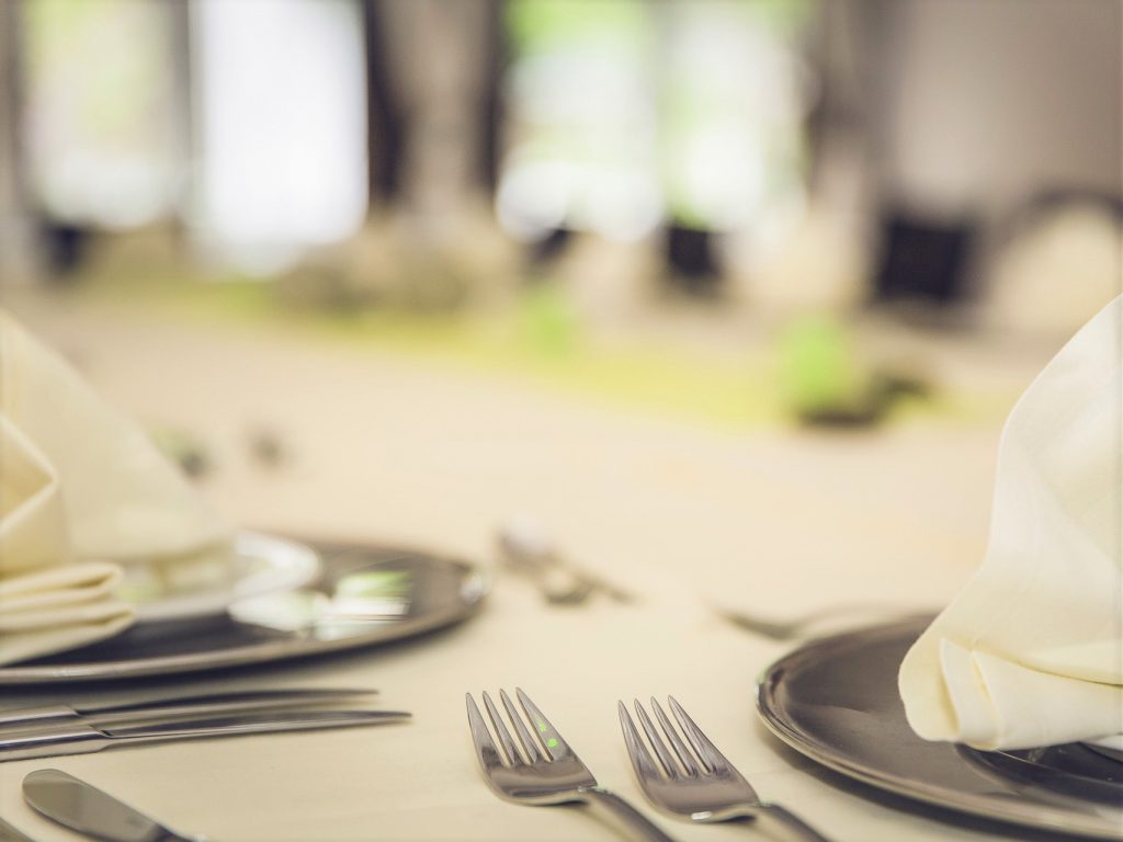 白いテーブルクロスの上にカトラリーとお皿が並んでいるパーティー会場の様子。
