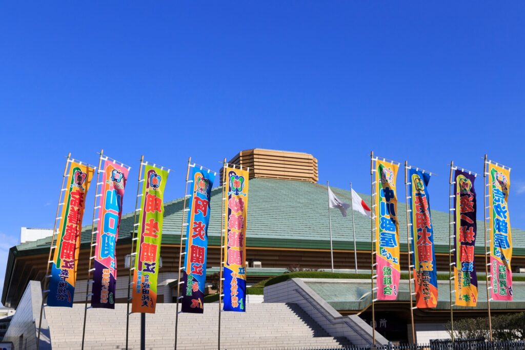Colorful sumo banners outside Ryogoku Kokugikan under a clear blue sky