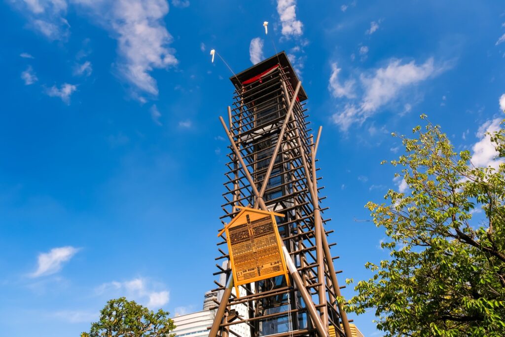 Yagura tower and banzuke board outside Ryogoku Kokugikan under a blue sky
