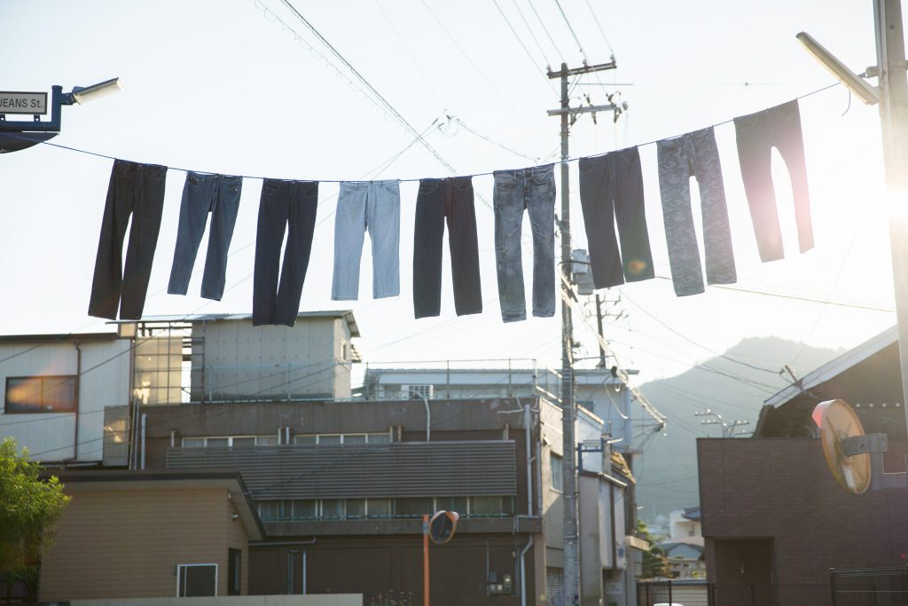 長い洗濯紐にジーンズがつるされ空が輝いている様子
