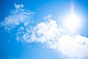 真夏日の日差しと青空（画面右中央に白く強く印象的に光る真夏の太陽。青空には対照的に白い雲、左上方に向けてうろこ状にたなびく）