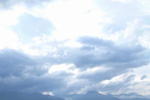 アルプスの山々と雲（はるか後方、画面下部にアルプスの山並み、画面いっぱい空いっぱいに雲。少し雨降りそうな、荒れ始めているような山の天気を彷彿とさせる。手前の上空は晴れているのか雲が白く光る）