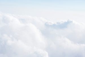 上空からの雲（飛行機の中から眺めたような雲海の景色。淡い水色、影には少し濃いめのグレー。光る部分が白く浮かぶ）