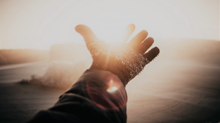 光に手を差し出している。手袋を付けた片手。