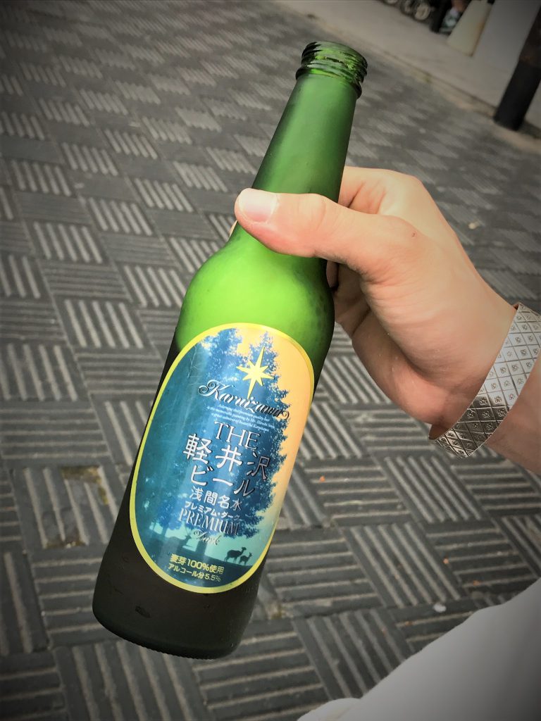 緑色の瓶に入った軽井沢のクラフトビールの瓶を手に持った写真。