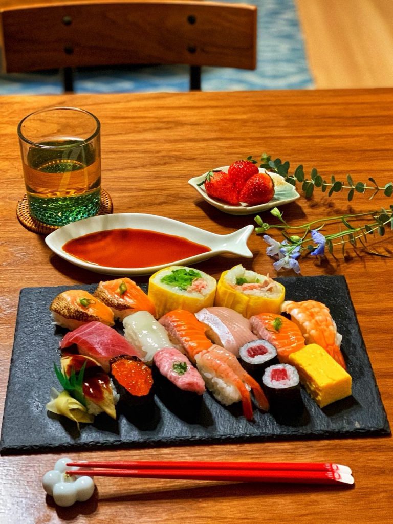 黒い皿に寿司が盛られ、魚をかたどった皿に醤油が盛られている様子。