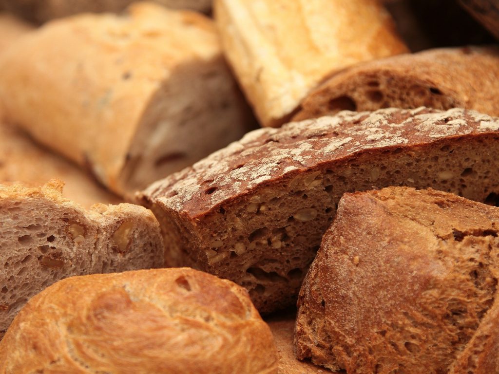 小麦色の様々な種類のパン(バゲットやカンパーニュなど）が積み上げられている写真