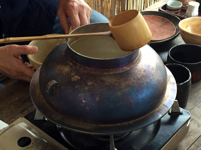 大きな茶釜に茶杓を添えている写真