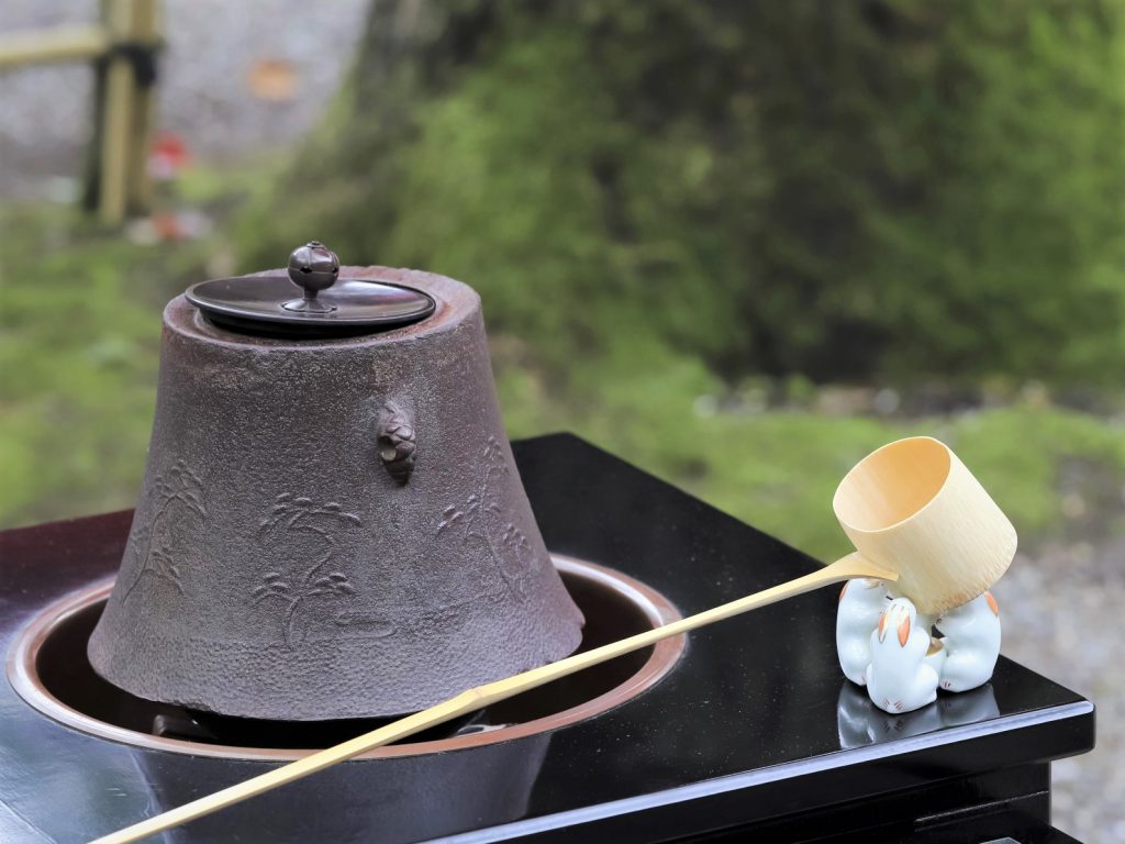 茶釜と茶杓が屋外に佇んでいる様子。