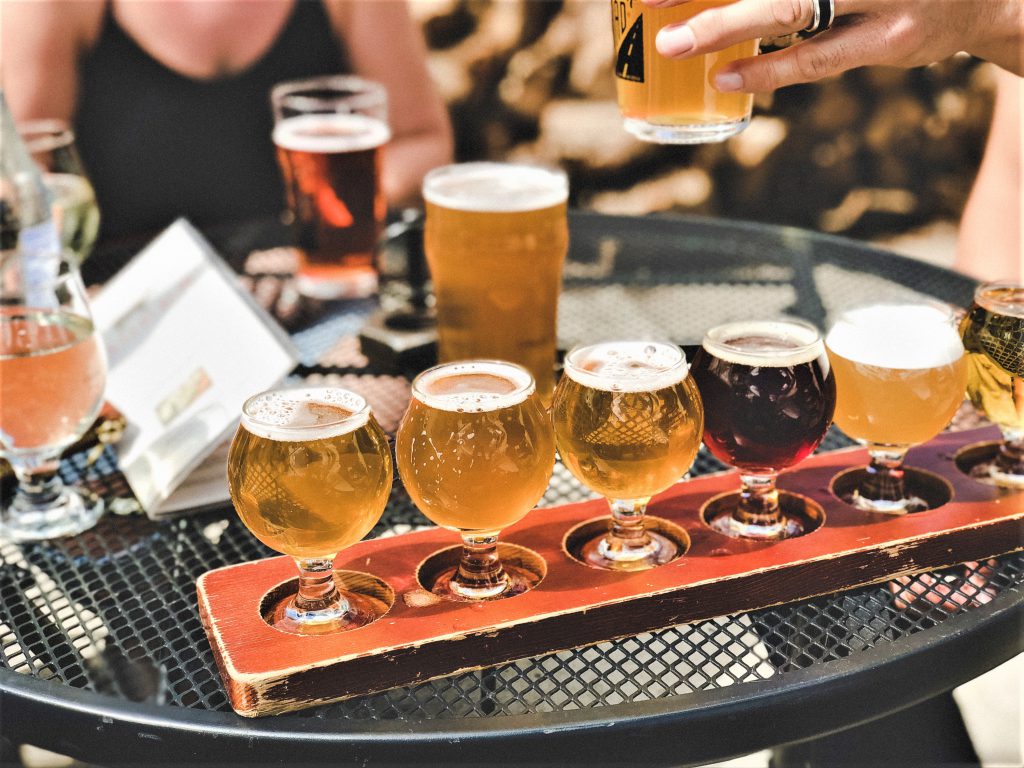 5つ色のそれぞれ違うクラフトビールが並べられている。その奥にはさらに違う種類のビールが大きなグラスに入っている。