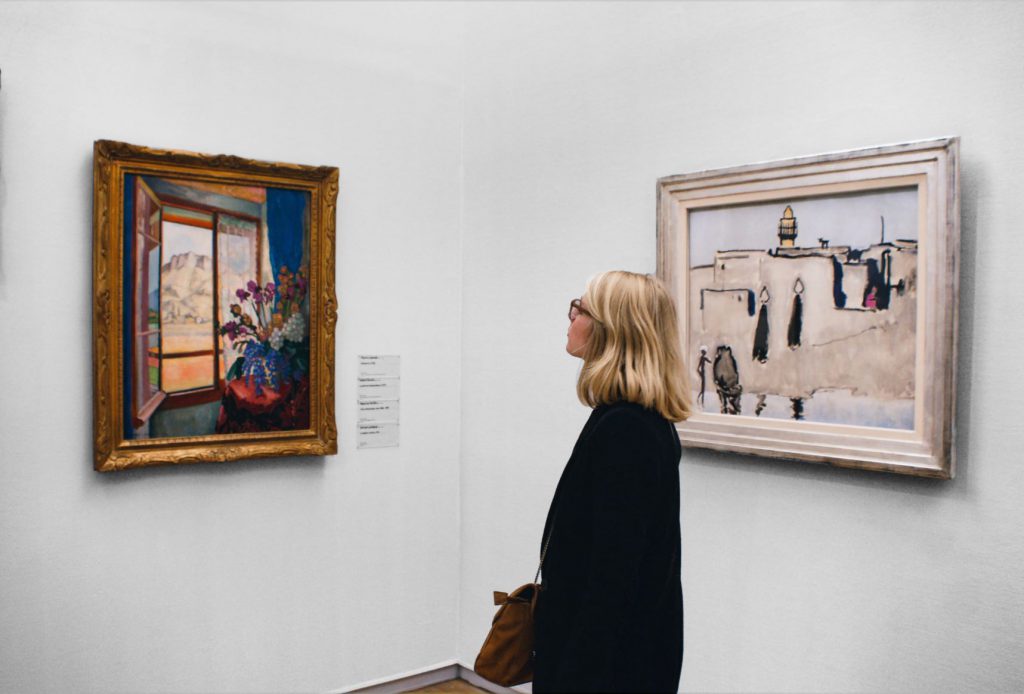 美術館の絵画を眺めている金髪の女性
