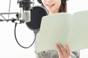 マイクに声を吹き込む女性声優の画像