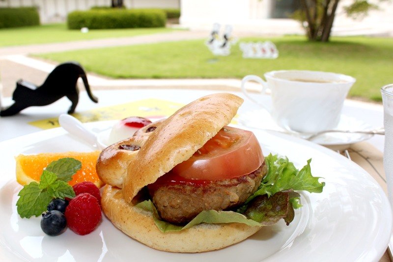 カフェの美味しそうなハンバーガー。肉の上に分厚いトマトがのっている。