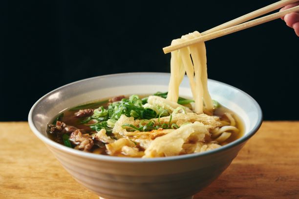 博多うどんの麺を箸で持ち上げている。