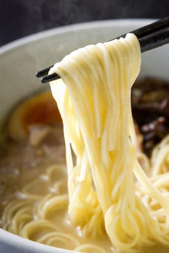 とんこつラーメンの麺を箸で持っている。