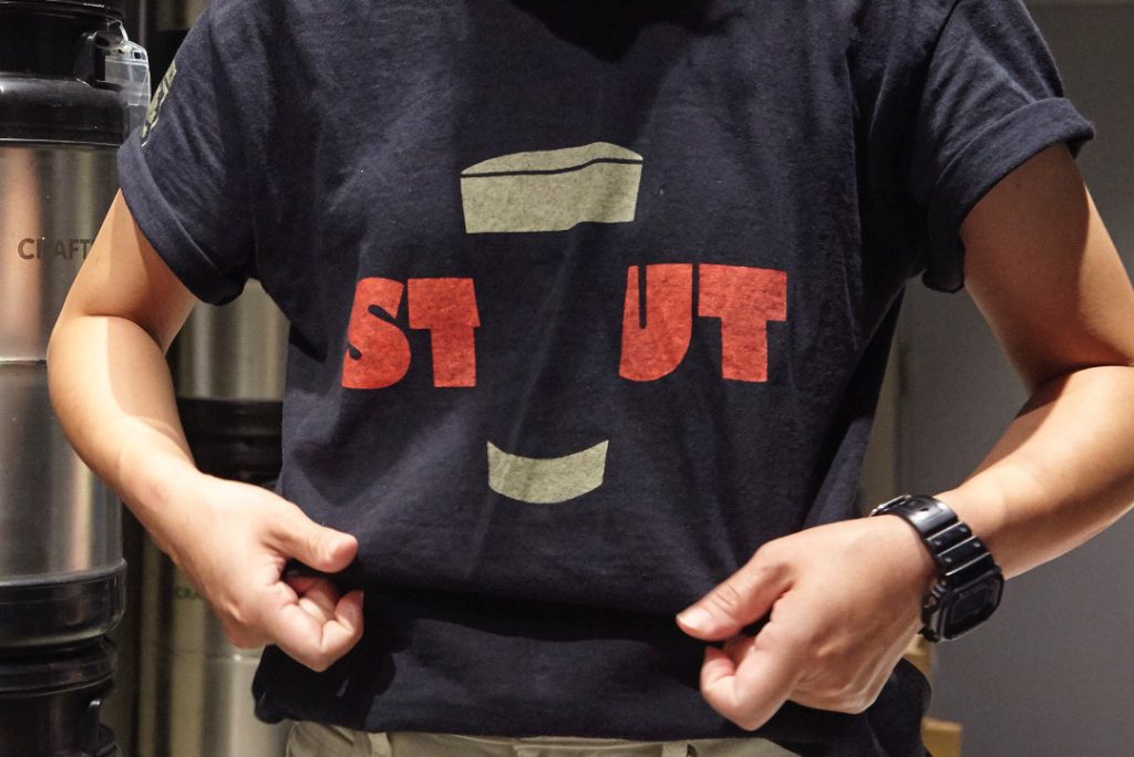 紺色のTシャツ。ローマ字で赤でSTOUTの文字。