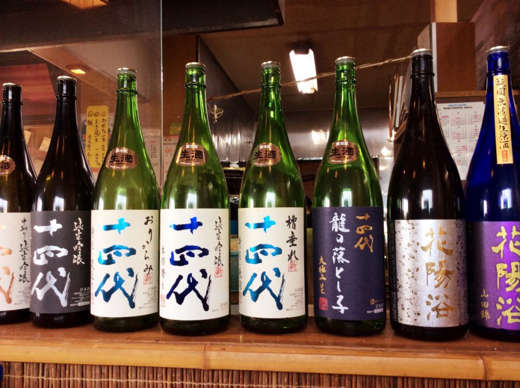 横須賀の「鴨鶴」のカウンターに並ぶ地酒と焼酎のボトル