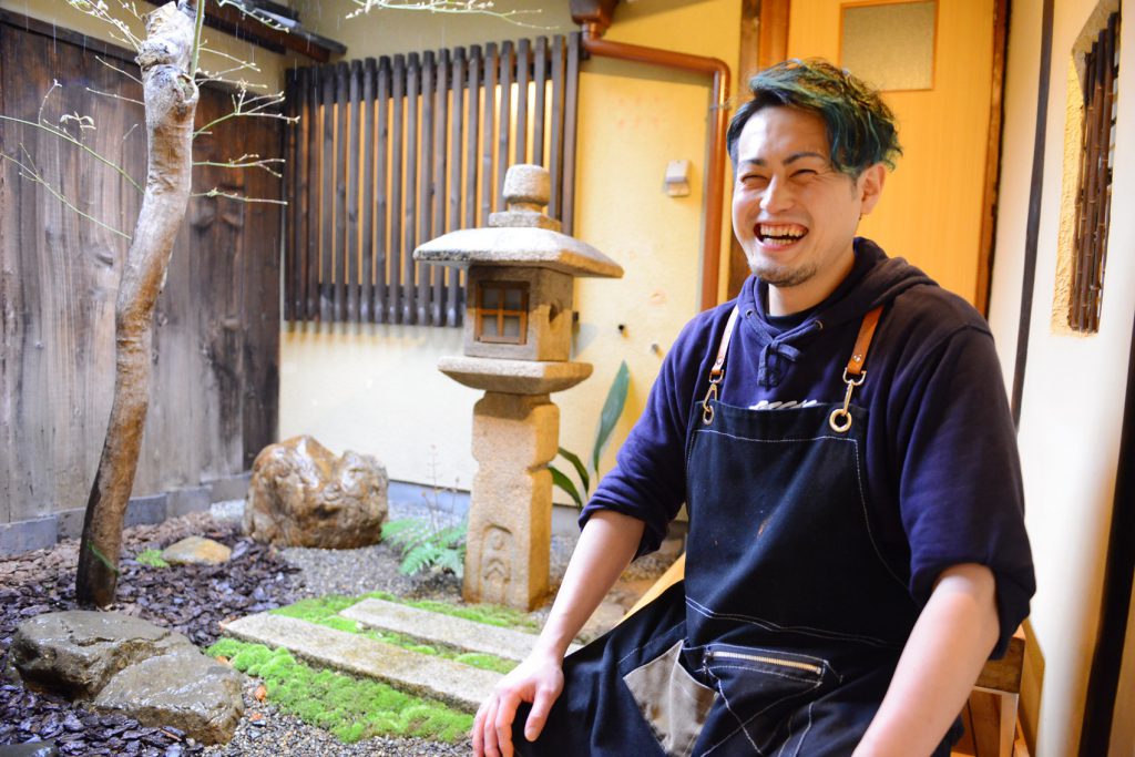 京都の風情を感じるお店の庭の縁側に座って話す満面の笑みの店主。
