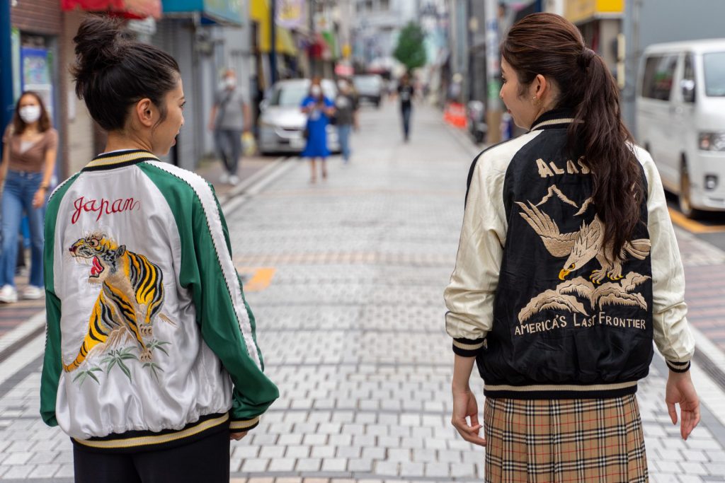 横須賀どぶ板通り商店街のメインロードをスカジャンを着て歩く女性二人