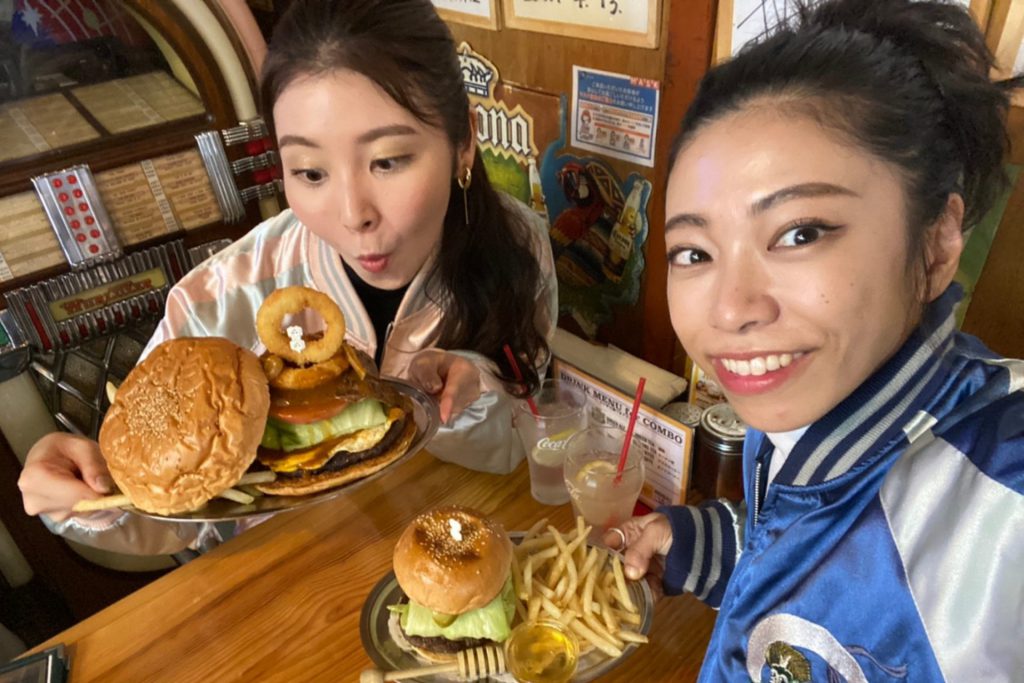 横須賀ネイビーバーガーの名店「HONEY BEE」でスカジャンを着てバーガーと記念撮影する女性二人