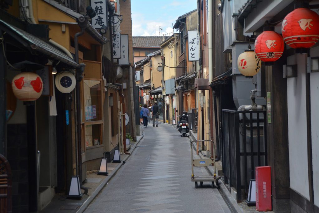 先斗町。道の両側に建物が並んでおり、軒先には赤や白の提灯が飾ってあります。