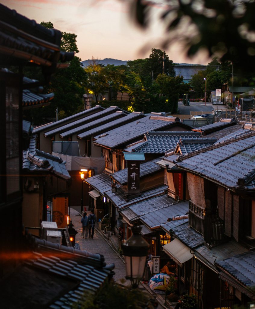 新橋通。２階ほどの建物から下を眺めたアングル。京都らしい瓦屋根、木造の家が道の両側に並んでいます。道の真ん中に後姿の男女が見えます。
