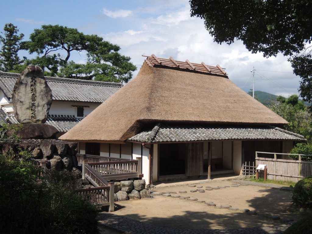 岩崎彌太郎の生家。建坪約30坪の茅葺きの平屋建て。左側に石碑が見えます。