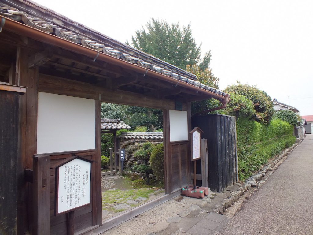 土居廓中・武家屋敷。瓦屋根で、白壁で下の部分は板になっている昔ながらの作りの屋敷。扉の左右に、屋敷の説明書きの看板が立てられ、入り口が解放されています。