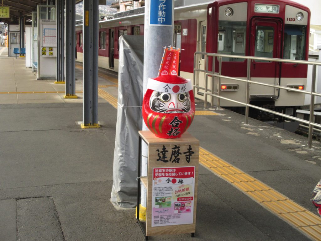 駅のホームに合格祈願だるまがある。