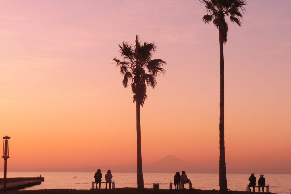 夕日で紅く染まる北条海岸。3組のカップル、夫婦がベンチに座っている。
