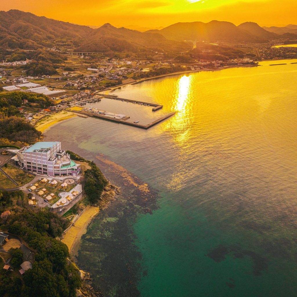 上空から夕日が美しい瀬戸内海を一望。海が夕日色に染まって美しい様子。