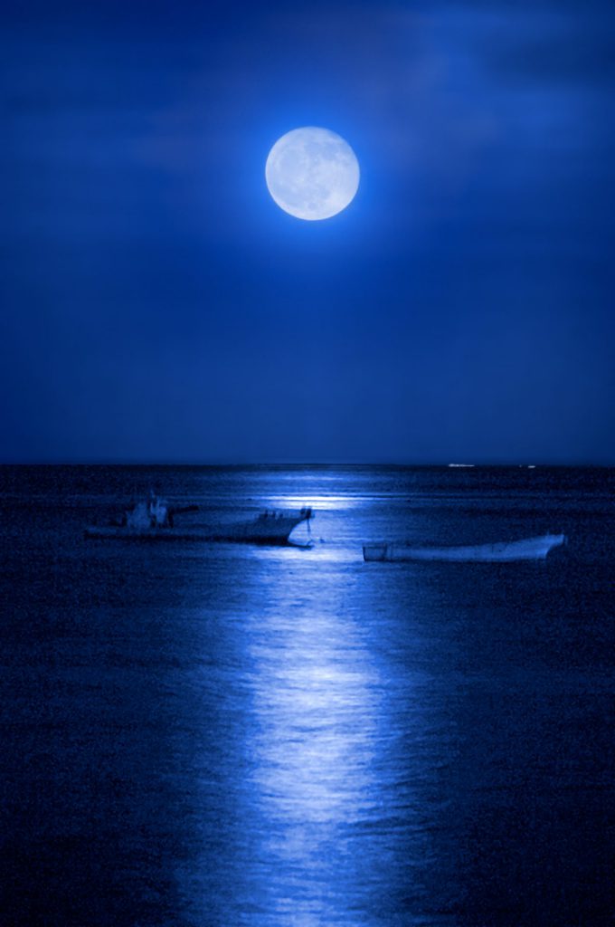 月が青い海の上に浮かび上がり、幻想的な雰囲気に包まれている。月の下には二艘の船が浮かんでいる。