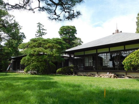 「旧大隈重信別邸・旧古河別邸」の外観。青い芝生の庭と日本式の木造建築の邸宅。