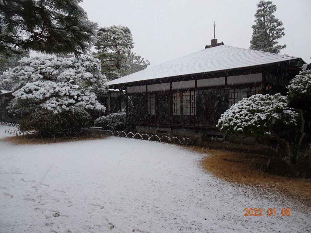 旧大隈重信別邸・旧古河別邸の木造日本建築と雪景色。庭と屋根に雪が積もっている様子。