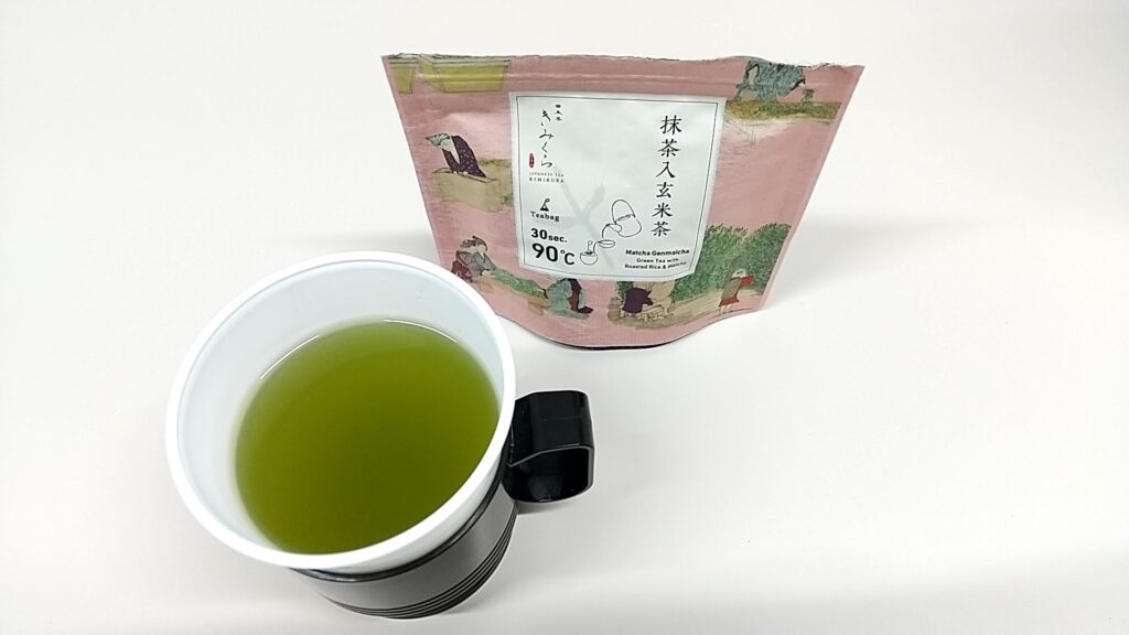 「日本茶きみくら」の日本茶「Art Print Package (Teabag) Collection」のうちの1つ、ピンク系のパッケージの商品。抹茶入玄米茶。パッケージ手前のコップにはお茶が入っている。