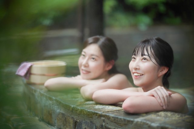 女性二人が温泉に浸かってくつろいでいる様子。