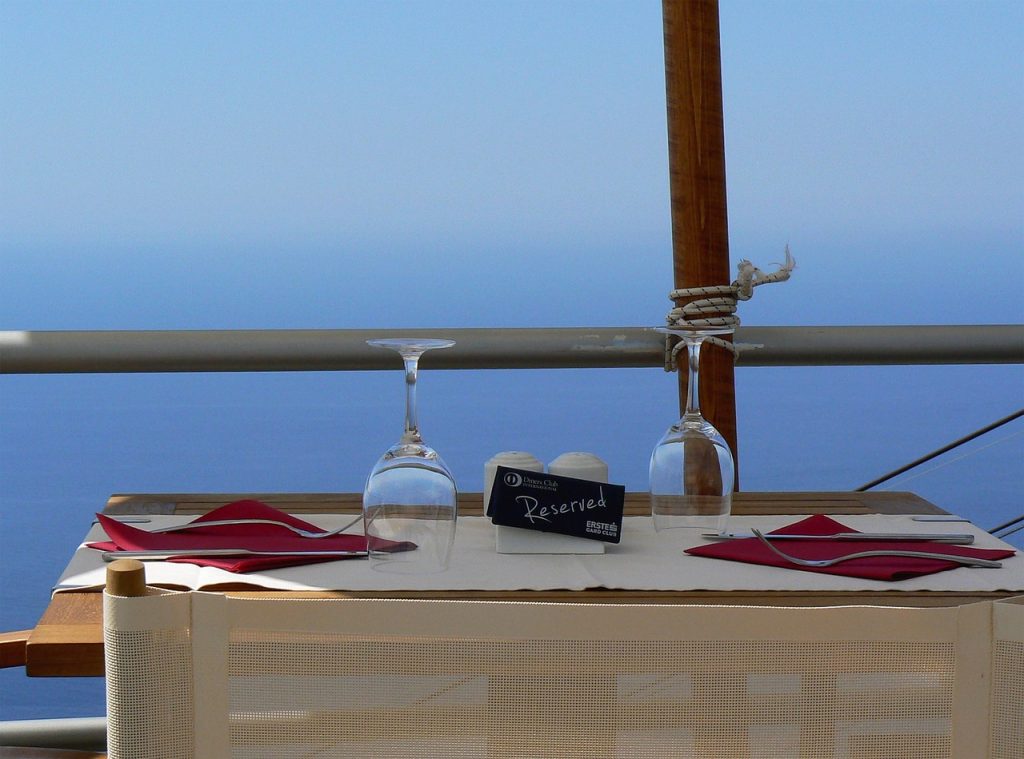 海を背景にテーブルが置かれ、伏せられたワイングラスとカトラリーが二つずつ用意されている。