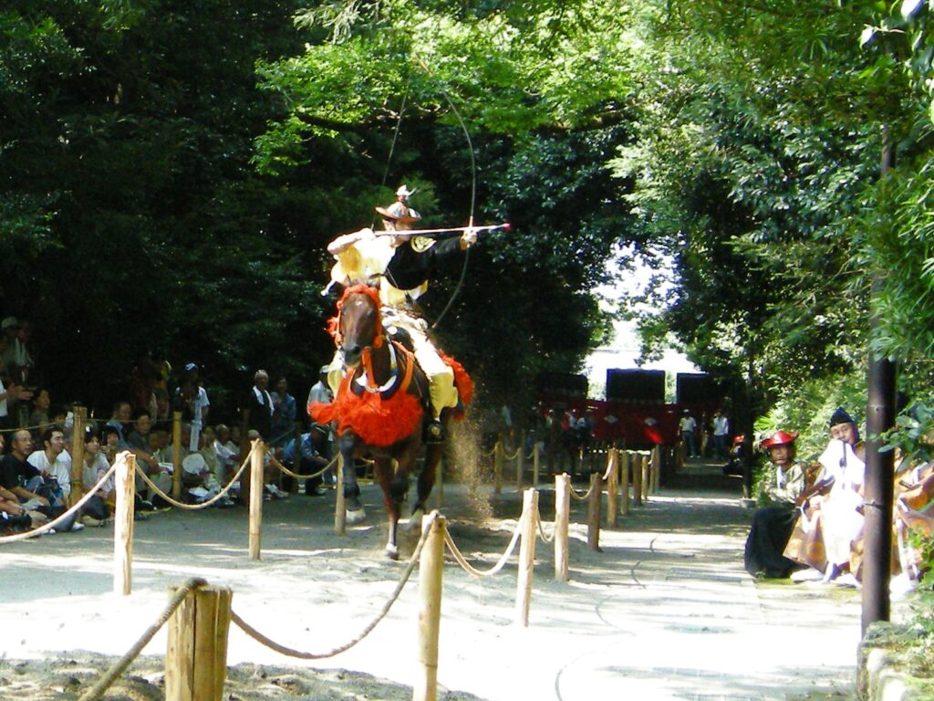 静岡県三島市の「三嶋大社」の「流鏑馬神事」の様子。馬に乗って走りながら、弓師が的に矢を射っています。