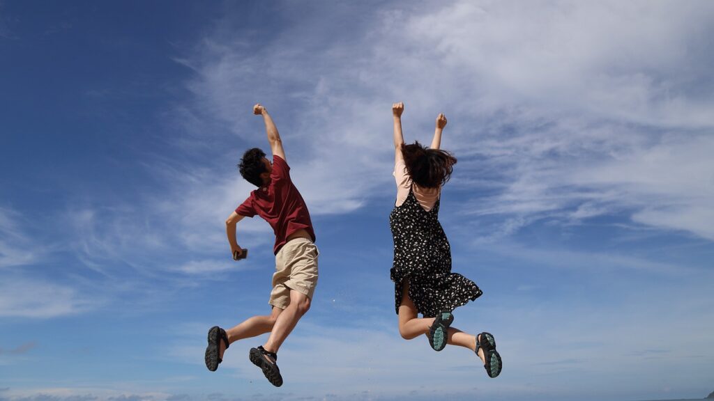 若い男女が空に向かってジャンプしている様子。
