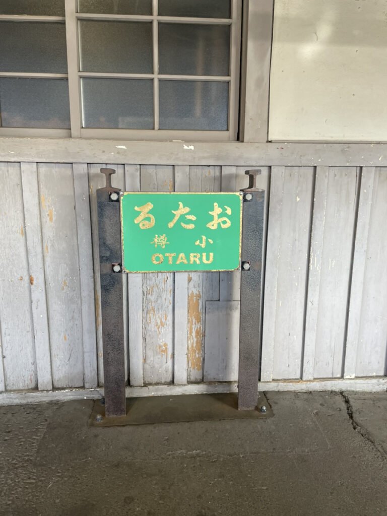 小樽の駅名標。緑の版に「るたお」（右読み）の文字。