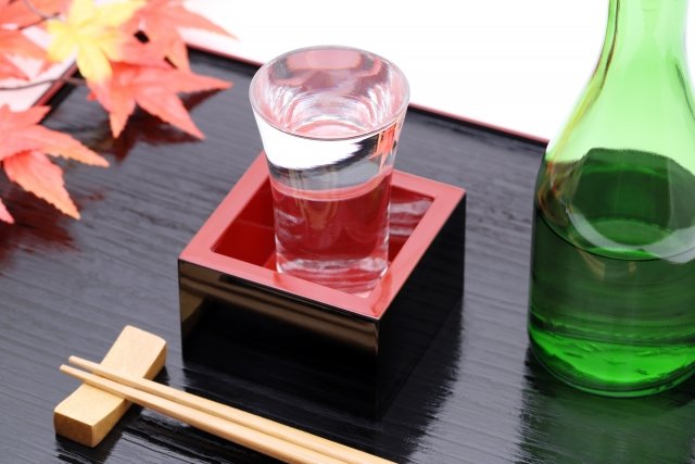 日本酒がなみなみと入ったグラスと枡。隣には緑色の酒瓶
