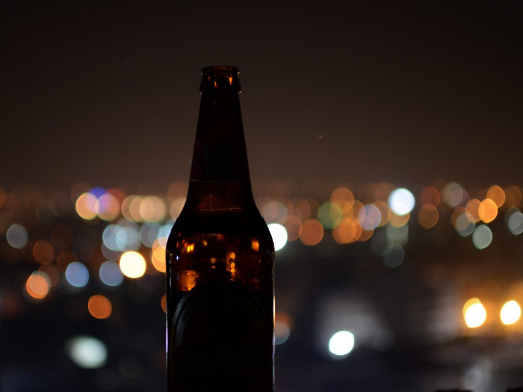 夜景をバックにクラフトビールの瓶が一本佇んでいる様子